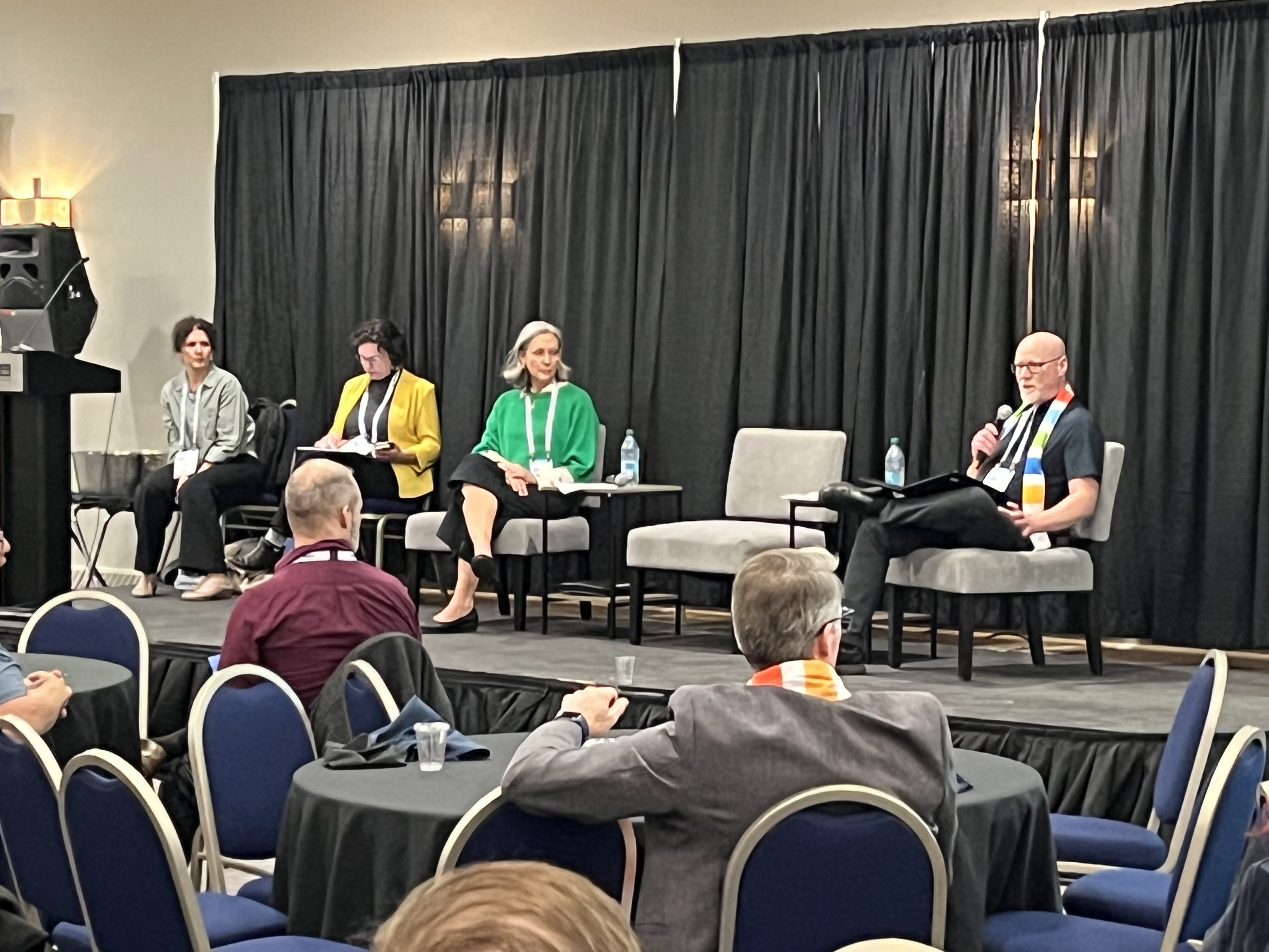 SPRA CEO seated with microphone on stage at SUMA Convention