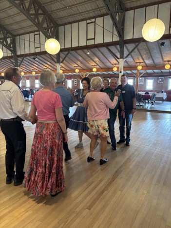 Group of square and round dancers moving hand in hand on dance floor